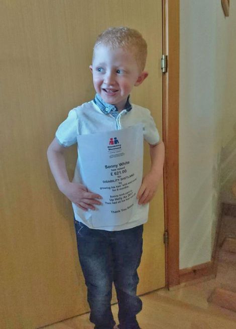 The five year old with a thank you letter from Disability Shetland after having his hair cut.
