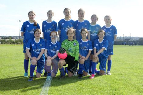 A group of girls in blue soccer uniforms posing for a picture.