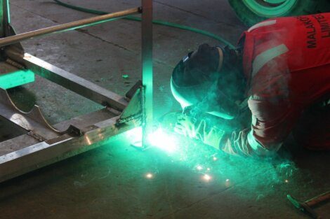 A welder using protective gear while welding metal components.