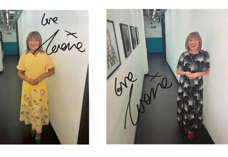 A woman in a floral dress smiling in a corridor with two signed photographs on the wall.