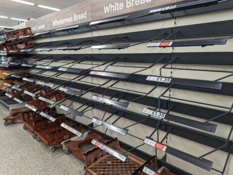 Empty supermarket shelves where bread is usually stocked, indicating a possible shortage.