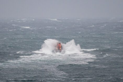 A lifeboat in rough sea conditions with waves crashing around it.
