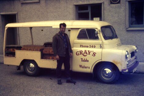 Man standing next to a vintage delivery van labeled 