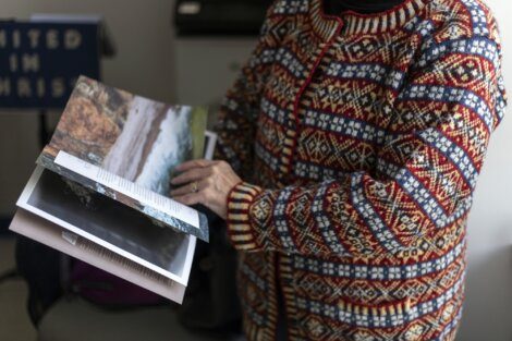 Person in patterned sweater browsing through a photography book.