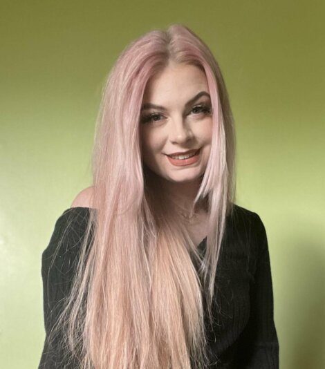 A woman with long pink hair posing for a photo.