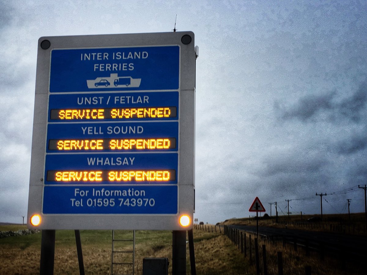 A sign on the side of the road that reads inter island service suspended.