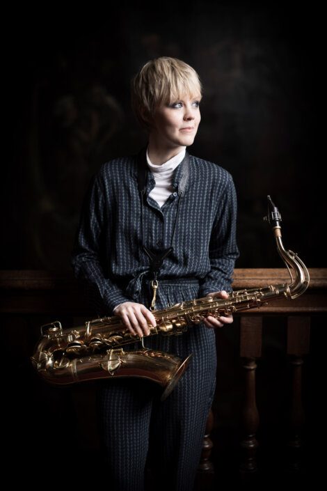 A woman holding a saxophone in a dark room.