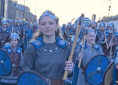 A group of people wearing viking helmets and shields.