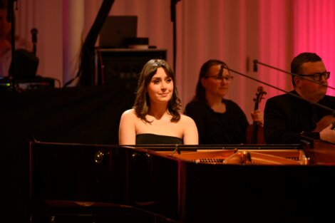 A woman playing a piano in front of a group of people.