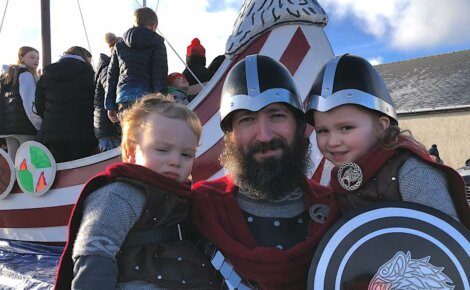 A man dressed as a viking poses with his children.