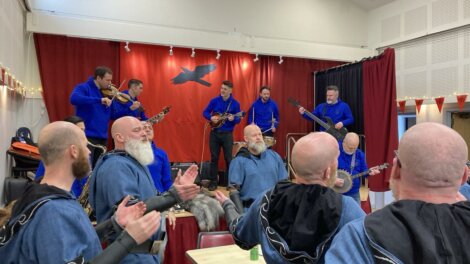 A group of men in blue robes playing music in a room.