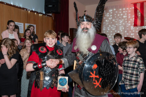 A man dressed as a viking shakes hands with a boy.