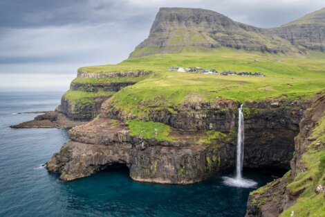 A waterfall on the edge of a cliff in the faroe islands.