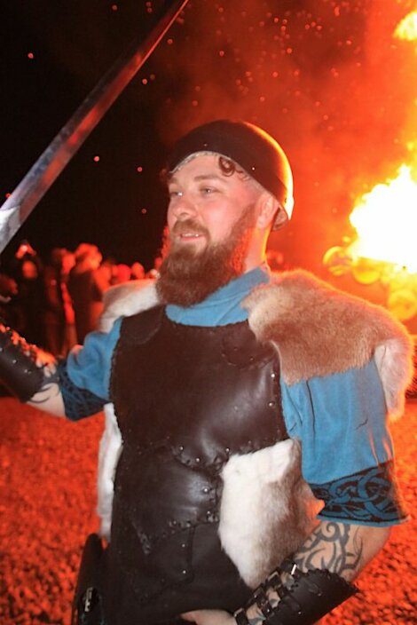 A man with a sword in front of a fire.