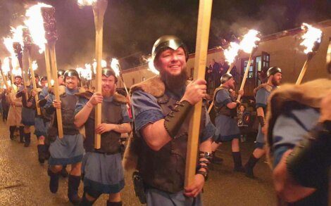 A group of men in clothing holding torches.