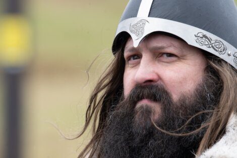 A bearded individual wearing a viking-style helmet.