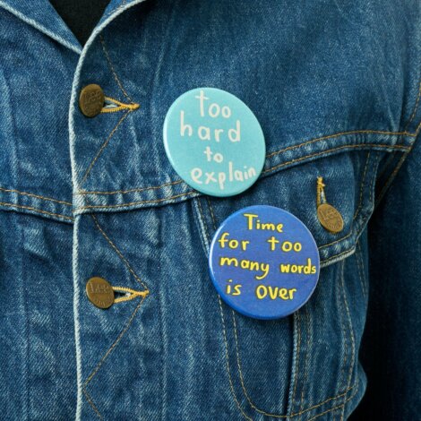 Denim jacket with two pins: one saying 